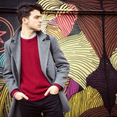 Young fashionable man standing in front of colorful wall. Autumn time outdoors.