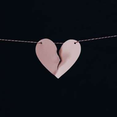 A paper heart with a broken piece of paper attached to a string Description automatically generated