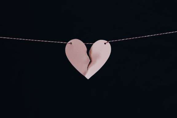 A paper heart with a broken piece of paper attached to a string Description automatically generated